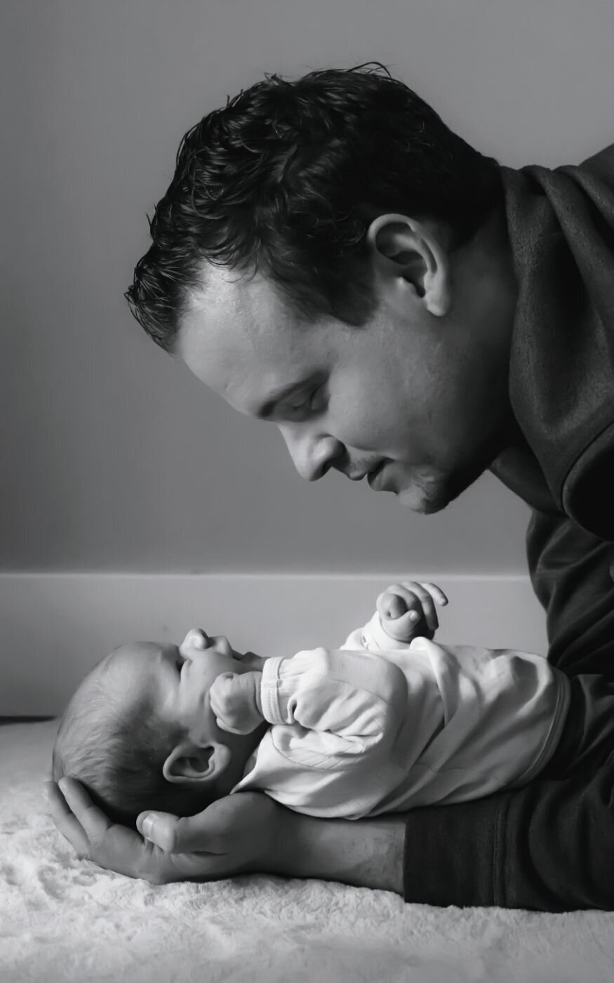 Intiem zwart-wit portret van een vader en zijn pasgeboren kind.