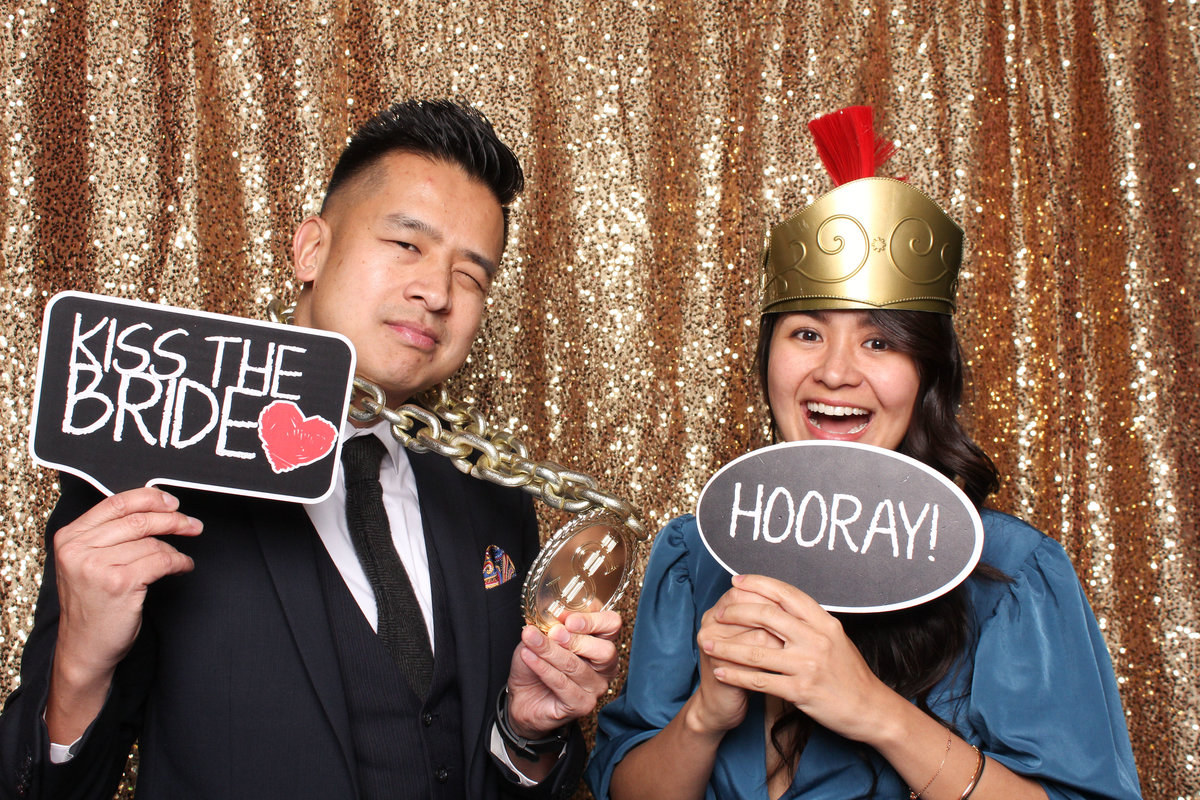 Couple having fun in a photo booth at a wedding using props