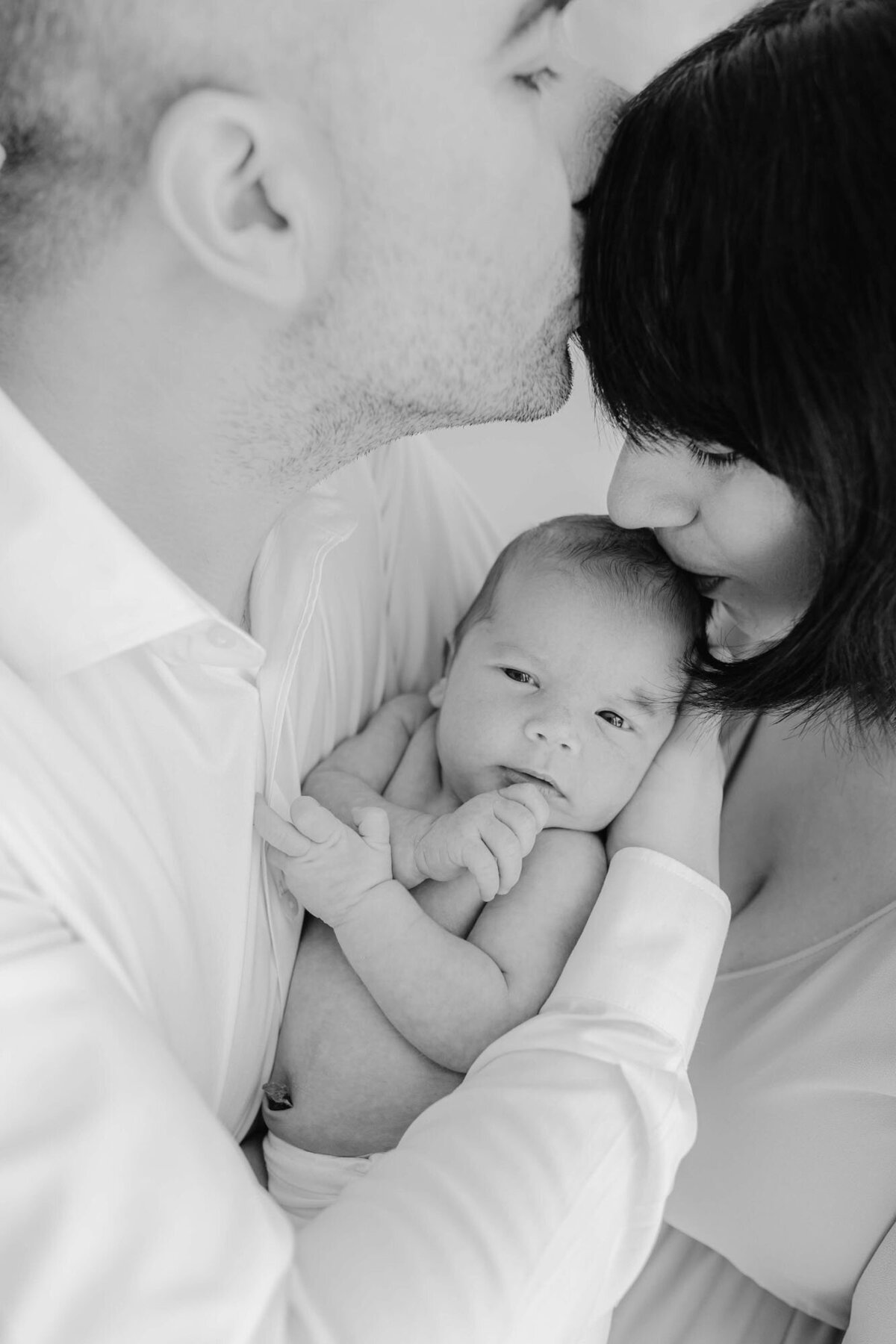 Tender moment of parents and baby in bedroom, Bay Area newborn family photography.