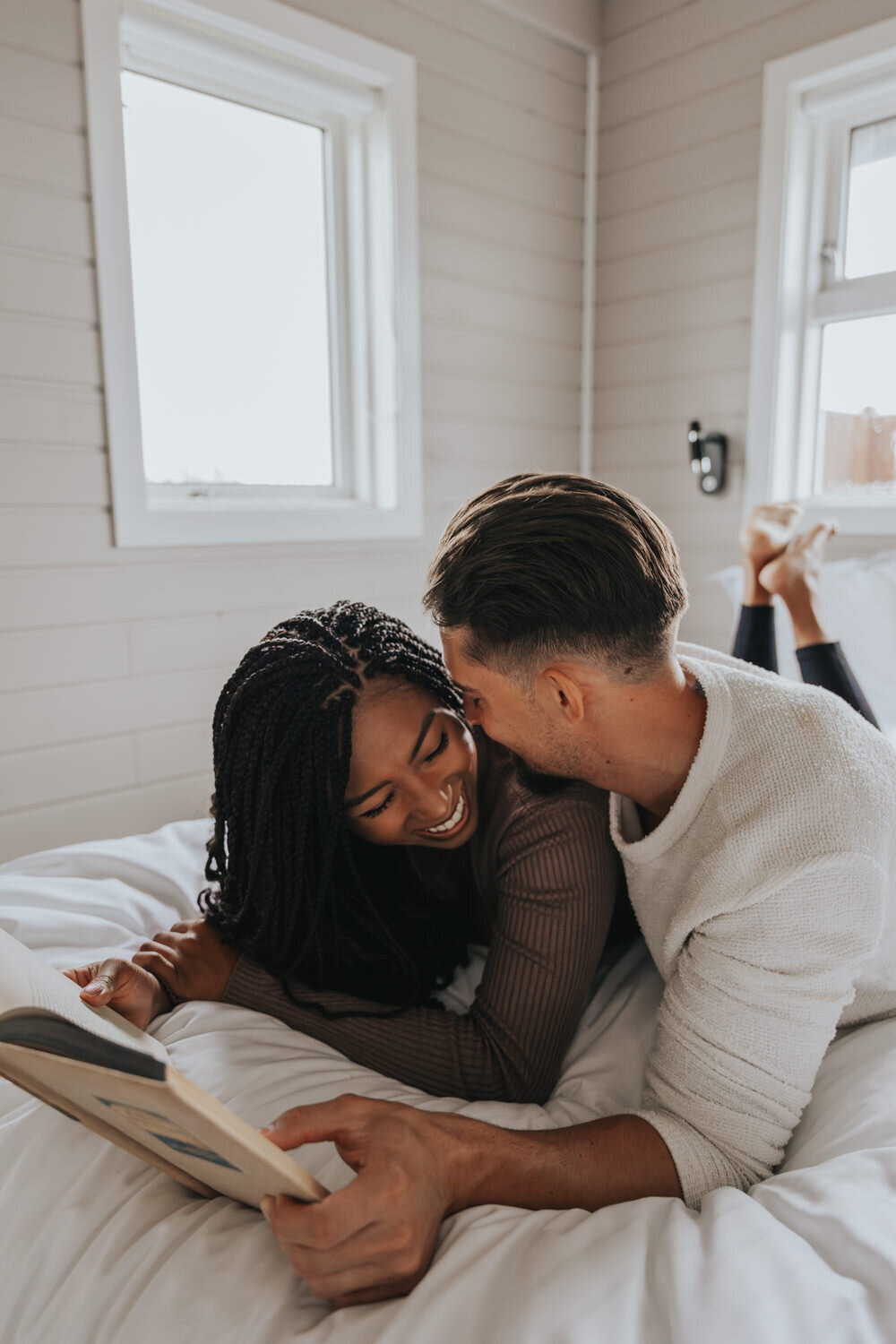 Husband whispers in wife's ear as they both smile widely 