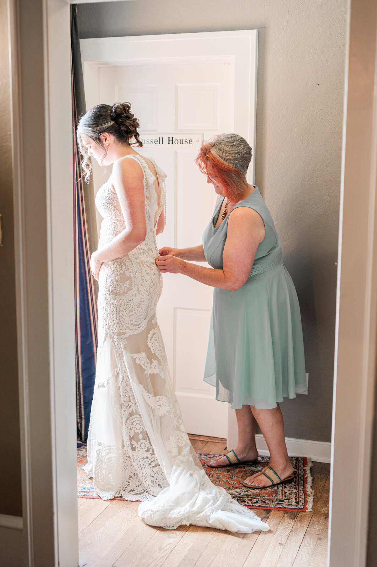 A person helping a bride zip up the back of her wedding dress