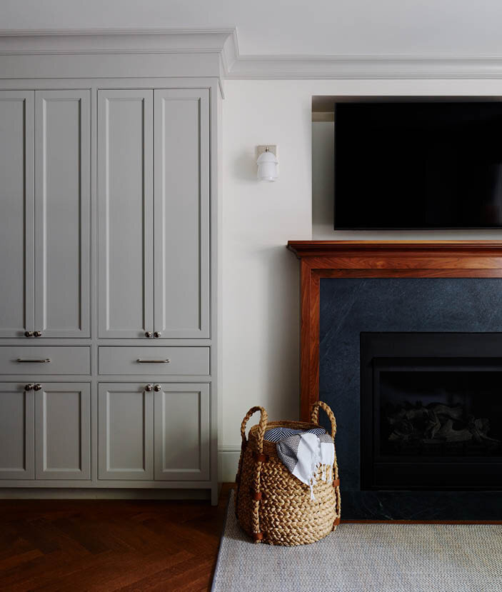 Custom cabinets meet a walnut and soapstone fireplace surround with mid-century sconces and a gas fireplace in this classic Boston brownstone. By Sarah Scales.