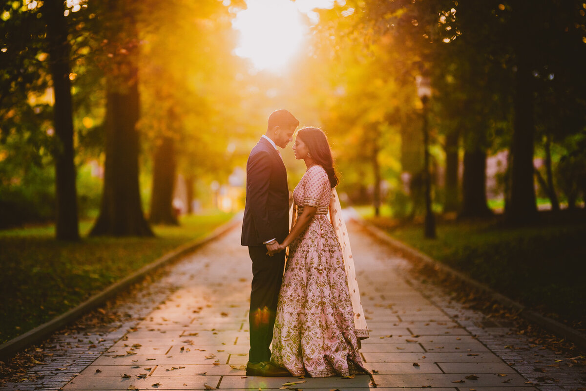 An engaged couple wearing traditional indian clothes holding hands at princeton university at sunset