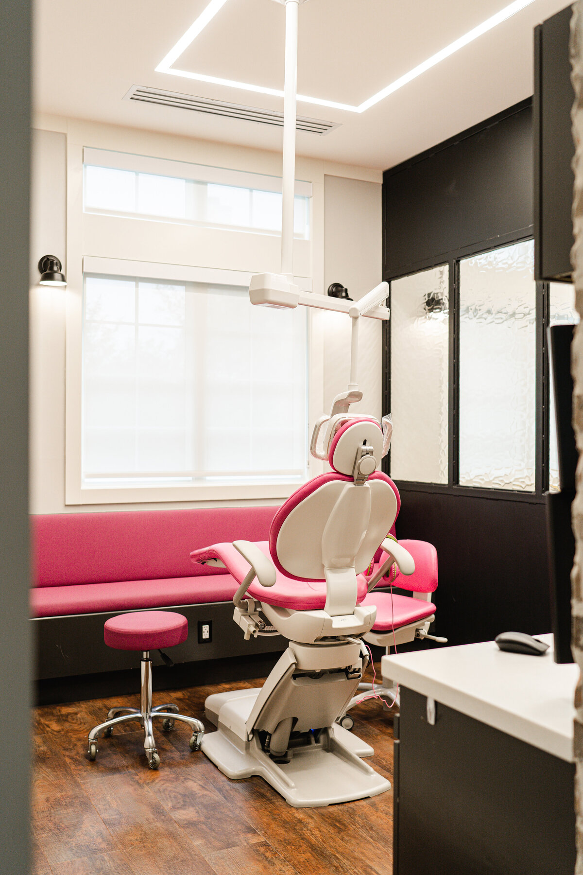 pediatric dentistry office patient room with pink couch and chair and rectangular light in ceiling