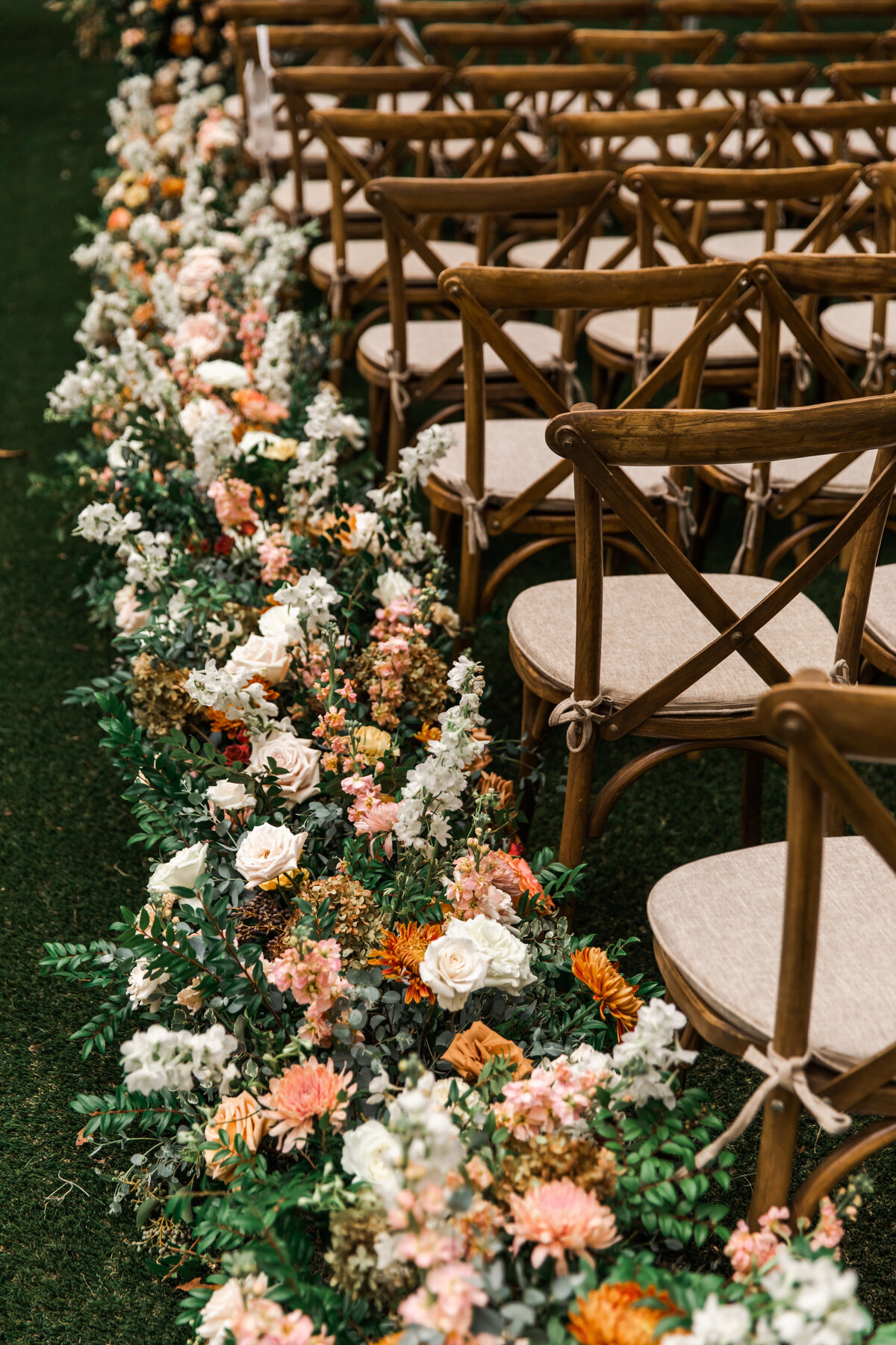 Lush floral hedges create aisle meadows for this fall wedding. Florals feature hues of terra cotta, blush, yellow, copper, and neutrals. Beautiful garden roses, dahlias, and fall florals highlight these arrangements. Design by Rosemary and Finch in Nashville, TN.