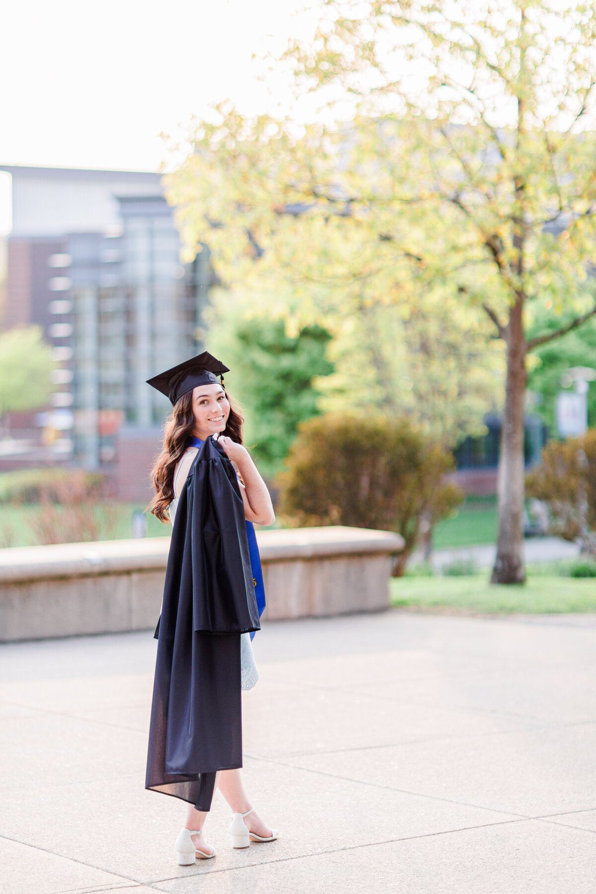 A girl with her graduation gown over her shoulder representing Boston cap and gown pictures