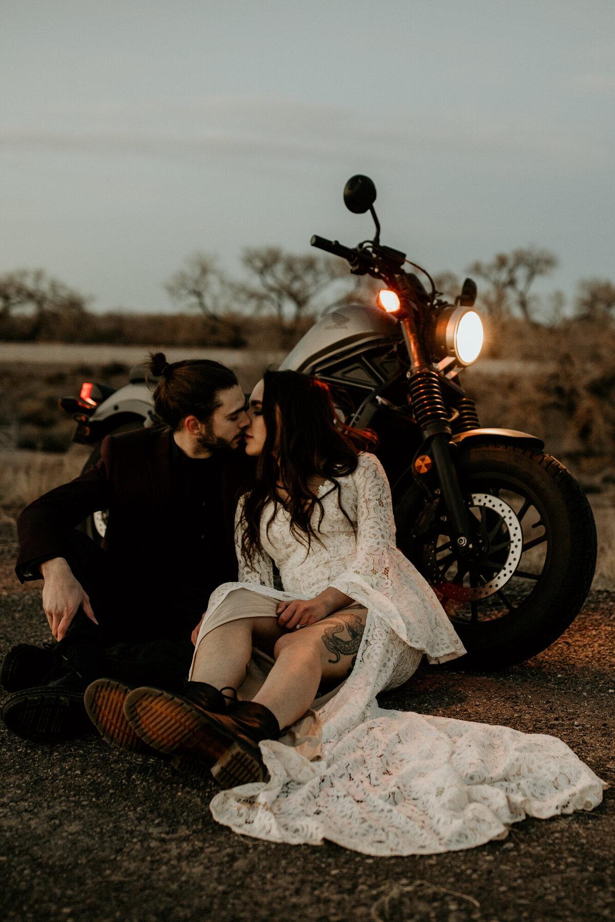 husband and wife sitting against a motorcycle