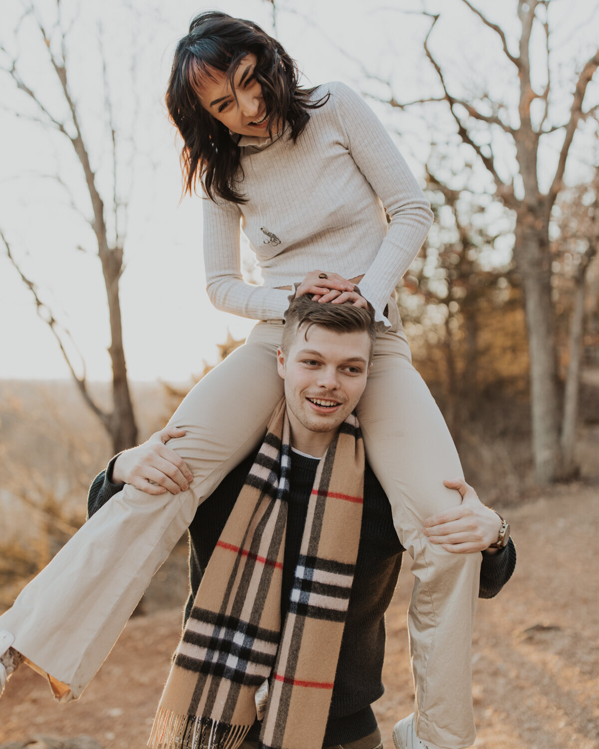 girl laughing while being held on boys shoulders during a fall photoshoot