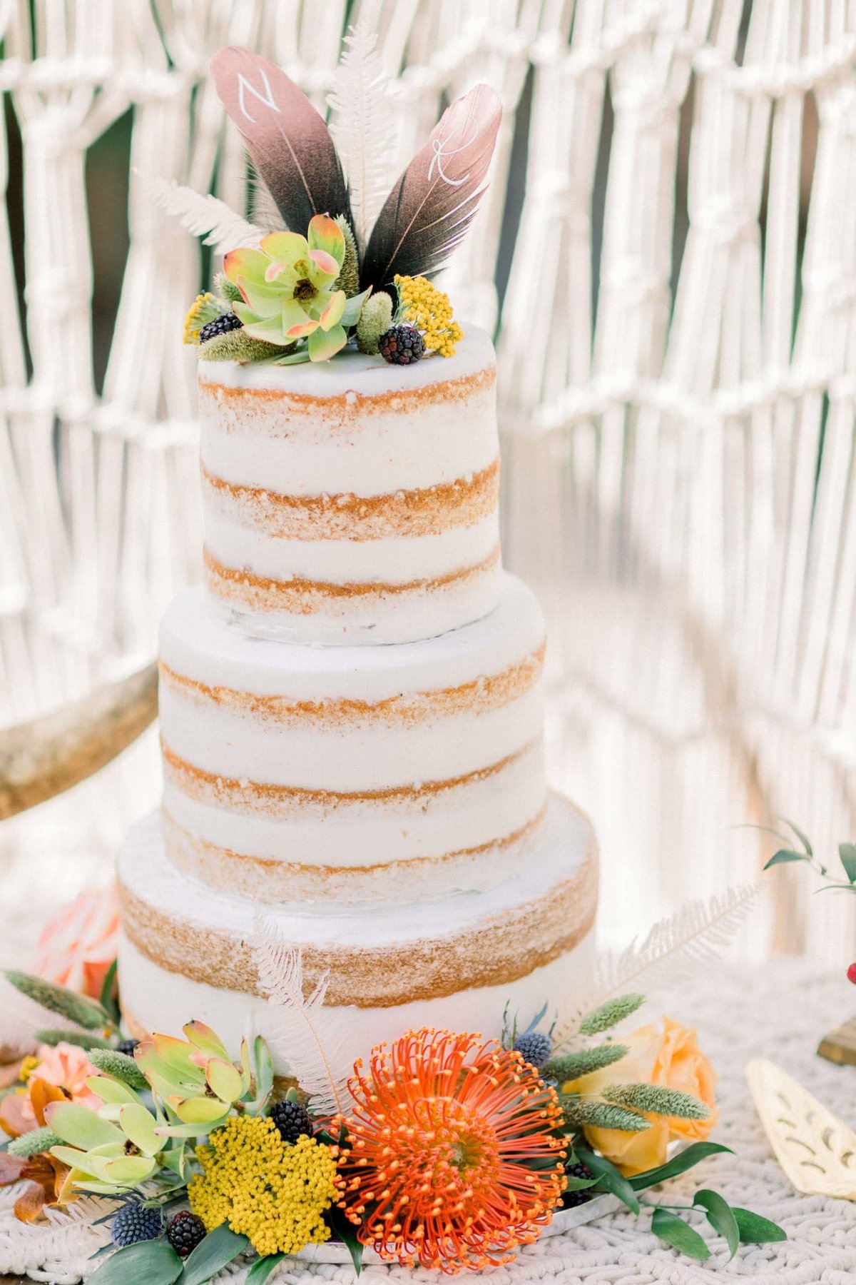 Beautiful 3-tiered white naked wedding cake decorated with an array of flowers