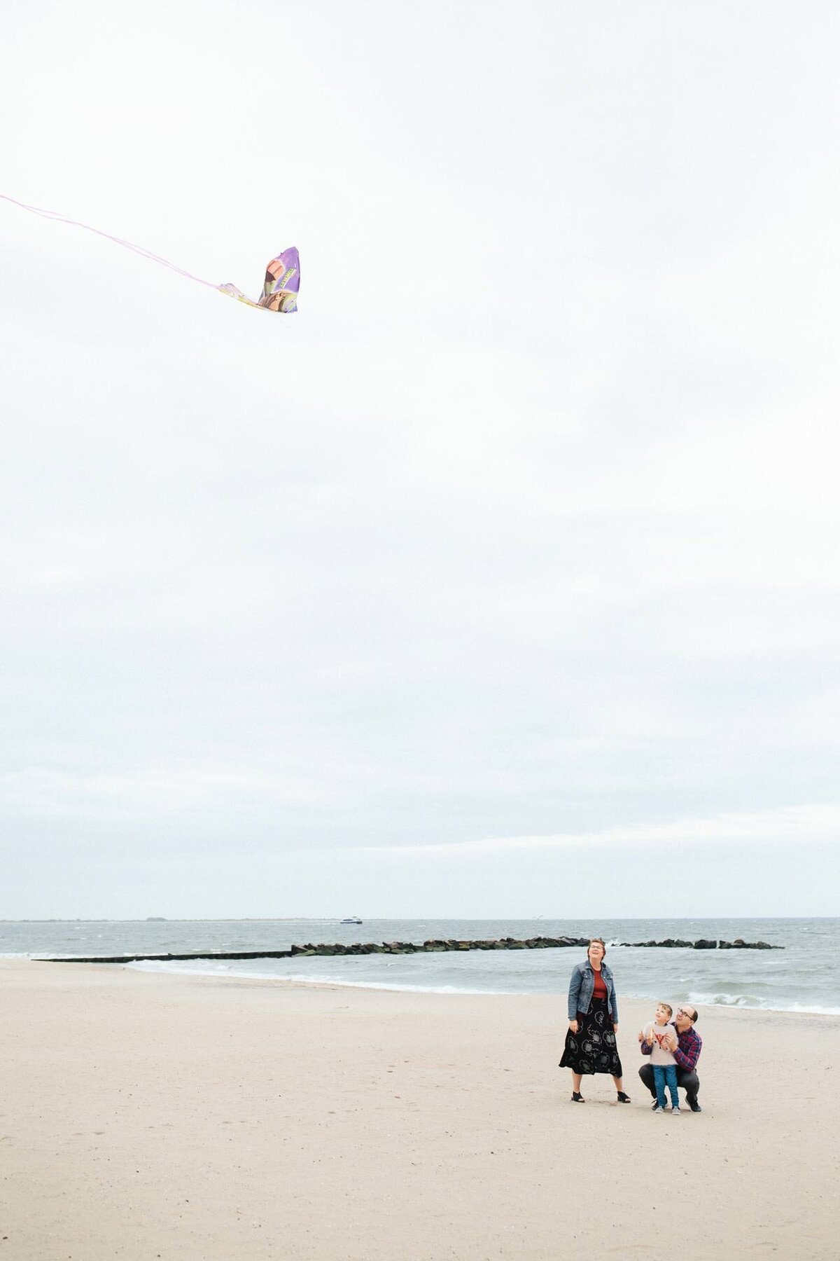 nyc family portrait photographer coney island family flying a kite along the beach