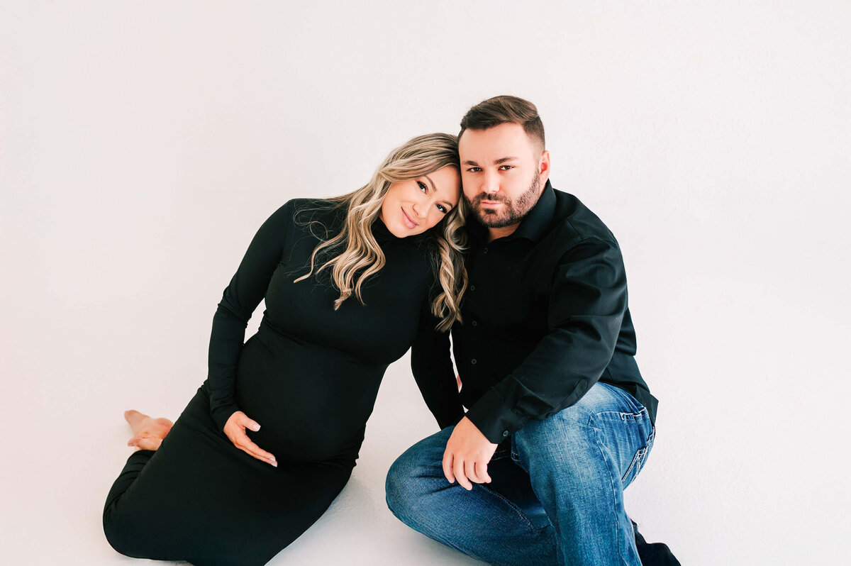 pregnant couple sitting on floor cuddling during Springfield MO maternity photography session