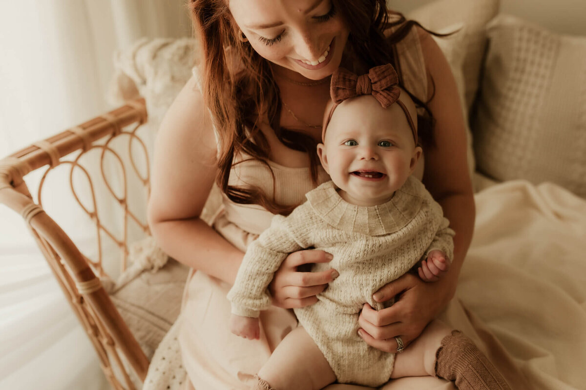 Mother holding her smiling baby girl while sitting down.
