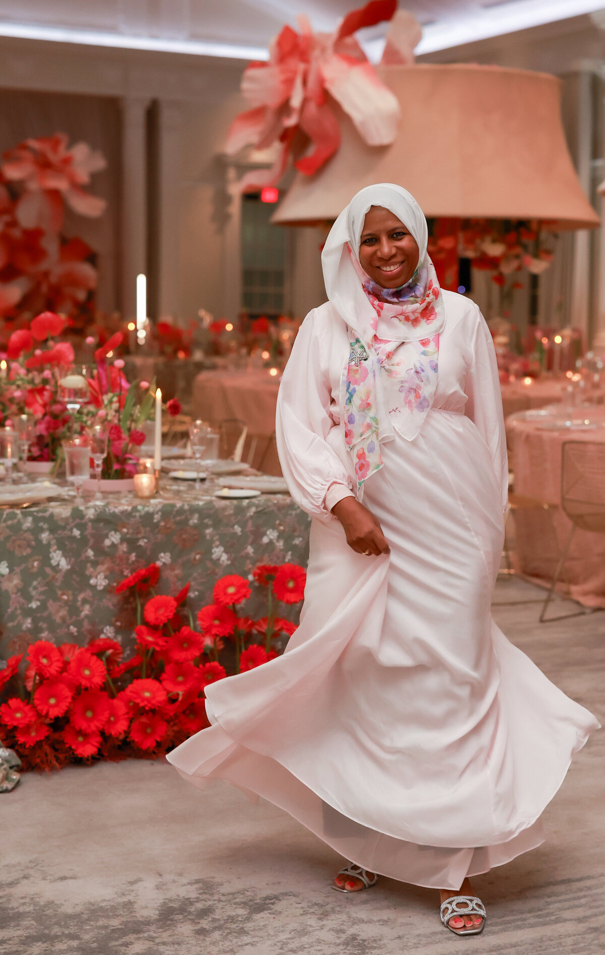owner designer planner wearing a stunning pink dress in a whimsical setting filled with lush florals, embodying elegance and creativity, designed by In Full Bloom Event Planning & Design