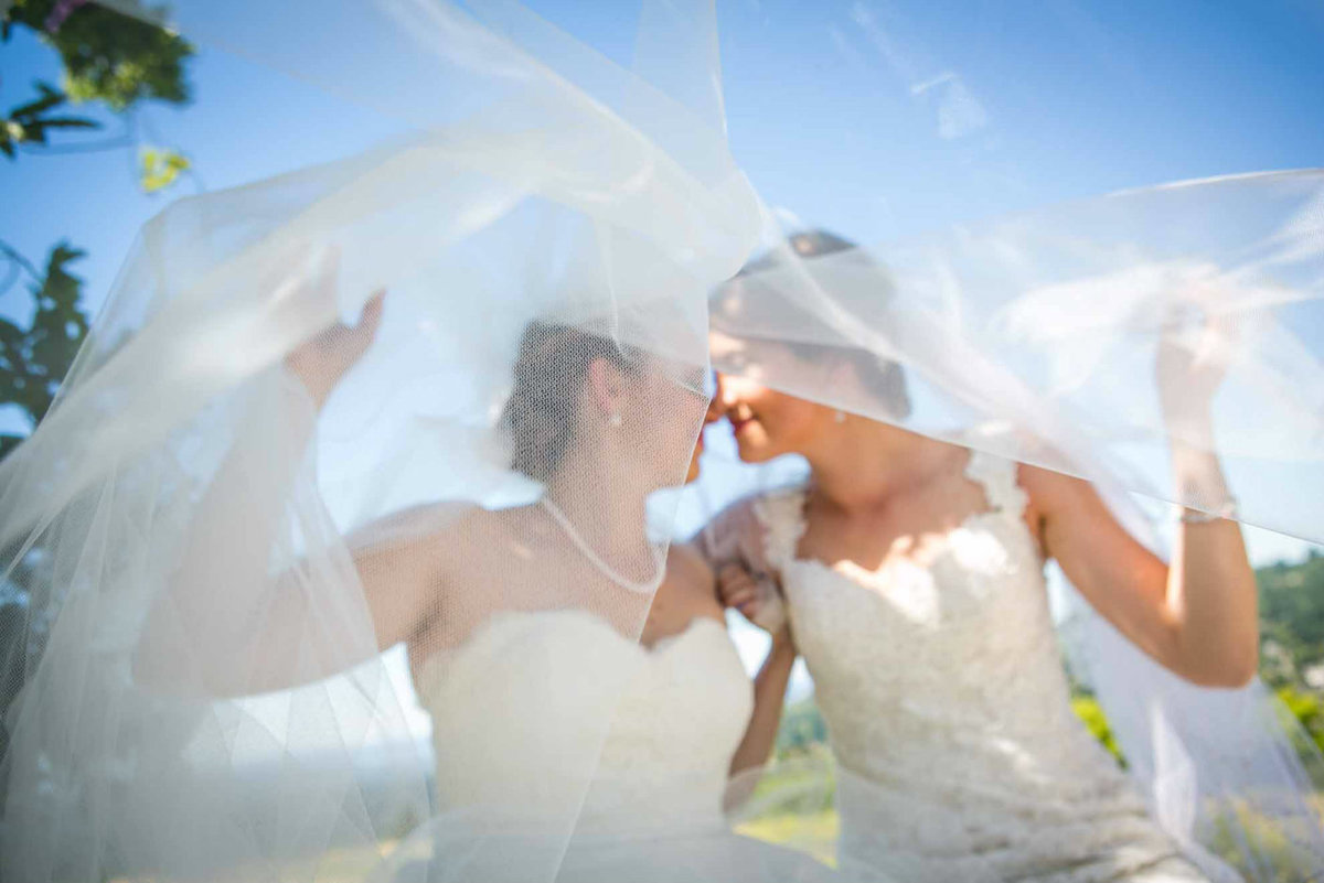 two brides kissing under vail