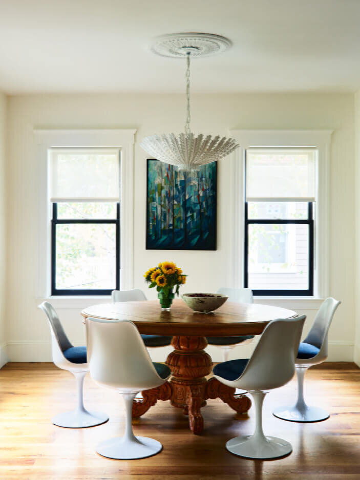 Luxury interior design in Boston features a vintage table paired with mid-century modern tulip dining chairs, blending classic charm with contemporary style.