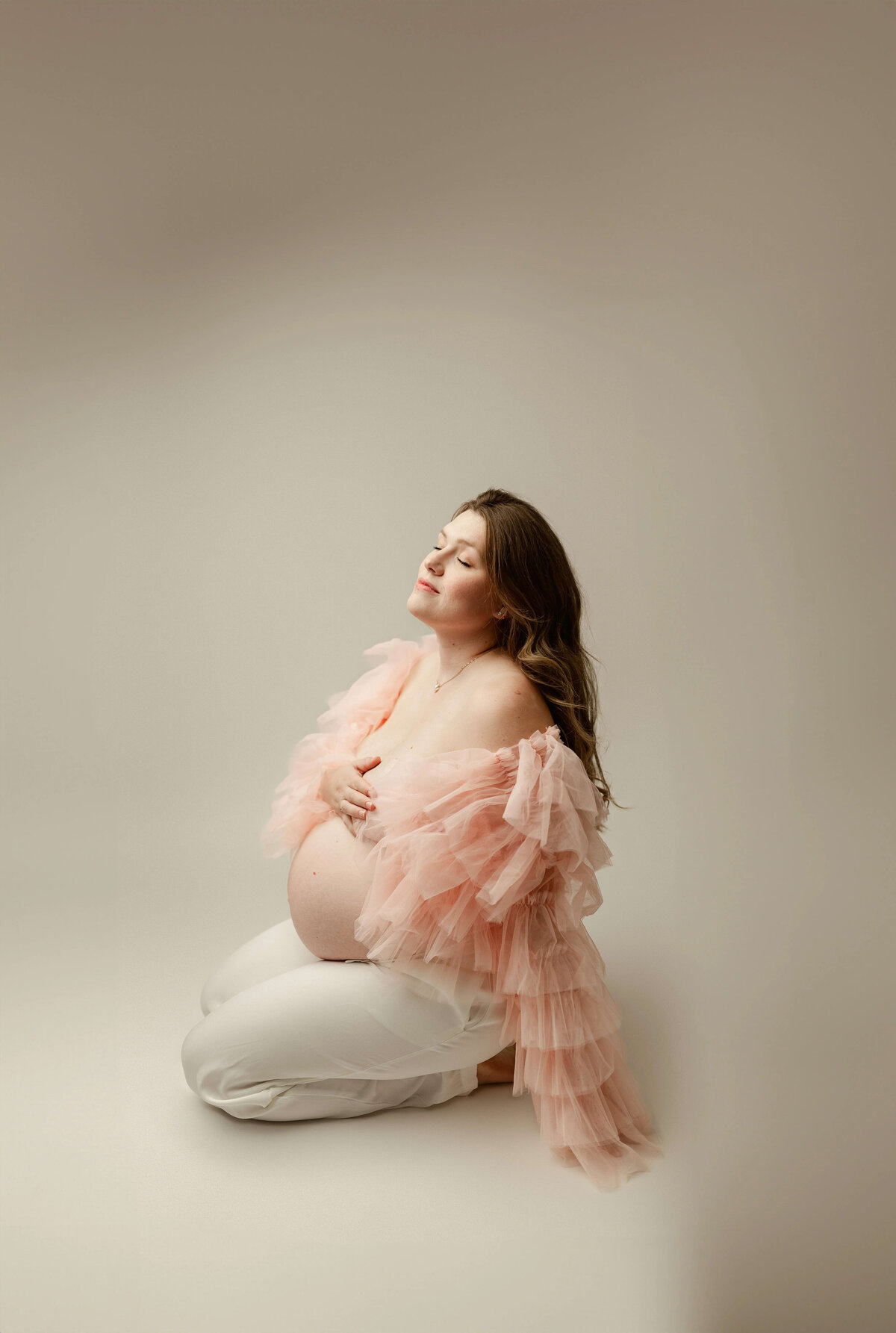 Seated maternity image with sheer pink robe in Maple Grove studio