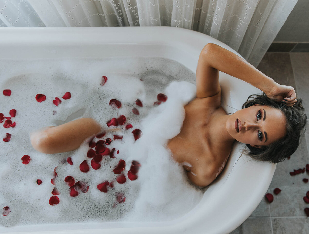 Woman posing in a bathtub with rose petals