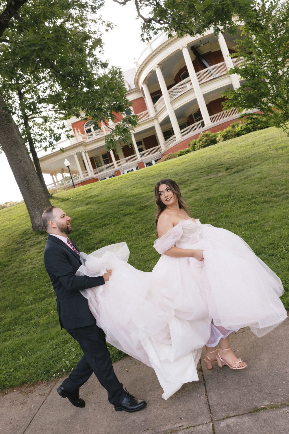 Bride and her groom assisting her with her gown walking outdoors