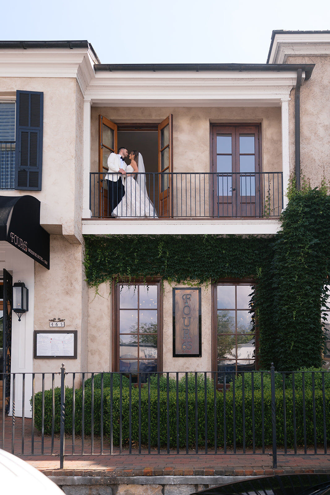 Bride and groom sharing a kiss on the balcony of Four65 Woodfire Bistro in downtown Highlands, North Carolina.