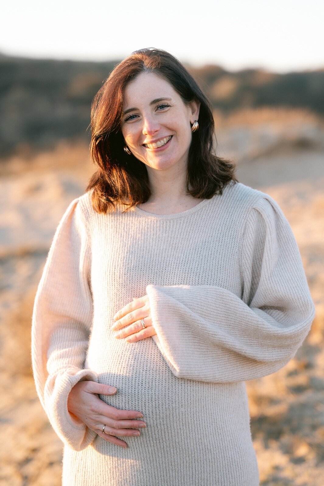 Zwangerschapsfotograaf legt zwangere vrouw lachend vast.