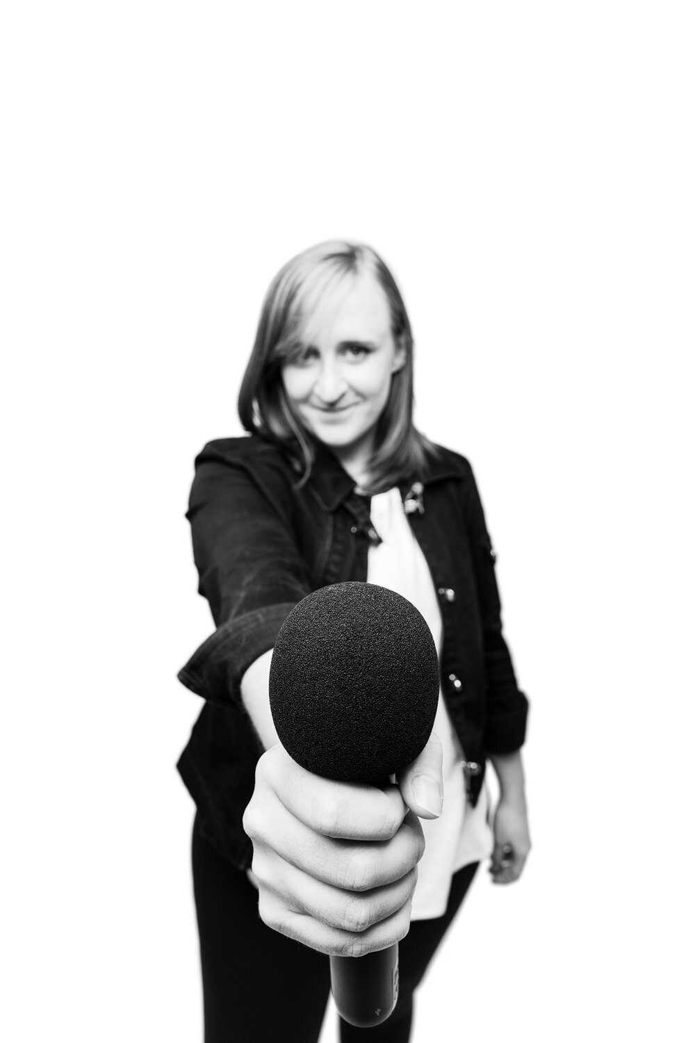 Dynamic editorial-style personal branding portrait of a comedian passing a microphone toward the viewer.
