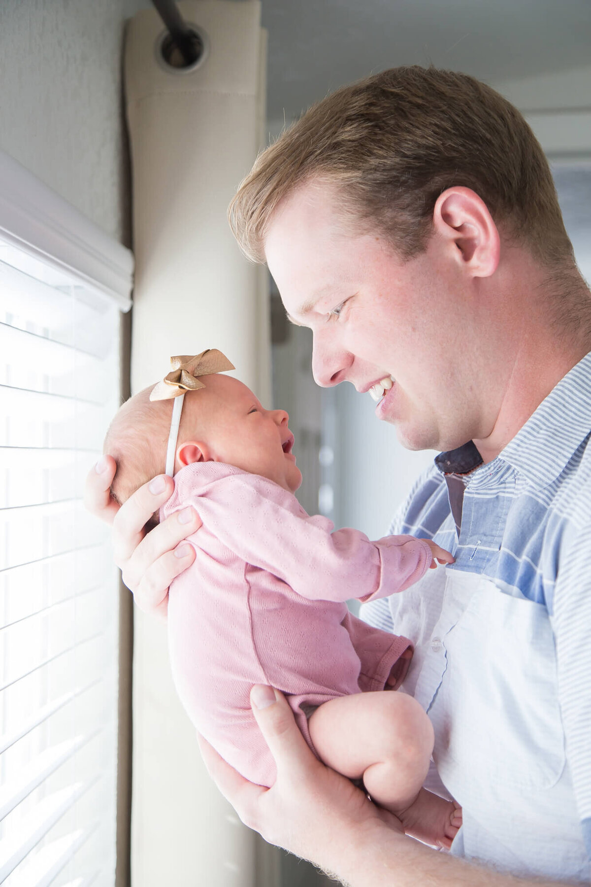 Father lovingly looking at newborn daughter, captured by jessica bowles