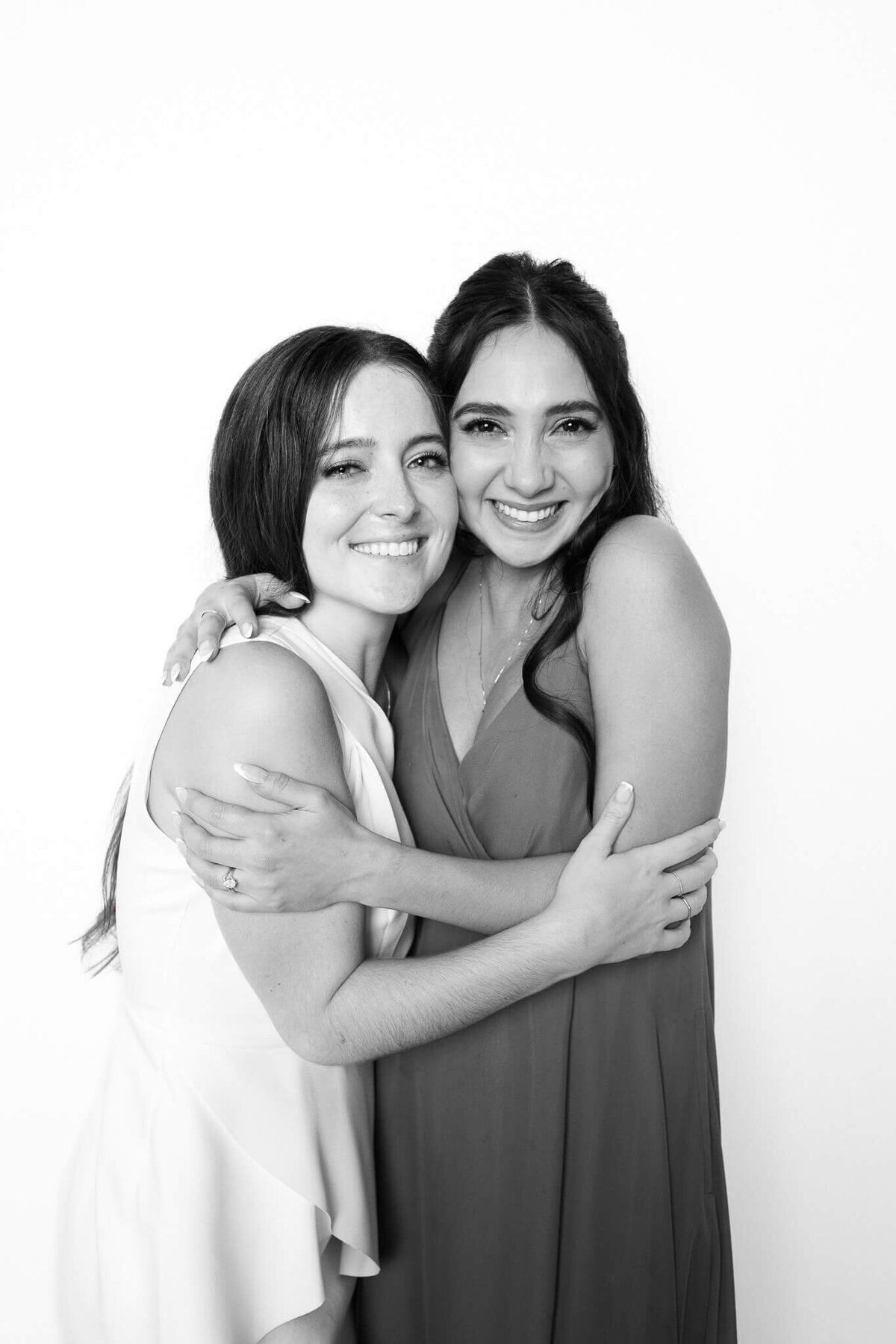 Two friends smiling and hugging in a black and white portrait captured by Monochrome Portraits, a modern portrait station in Phoenix.