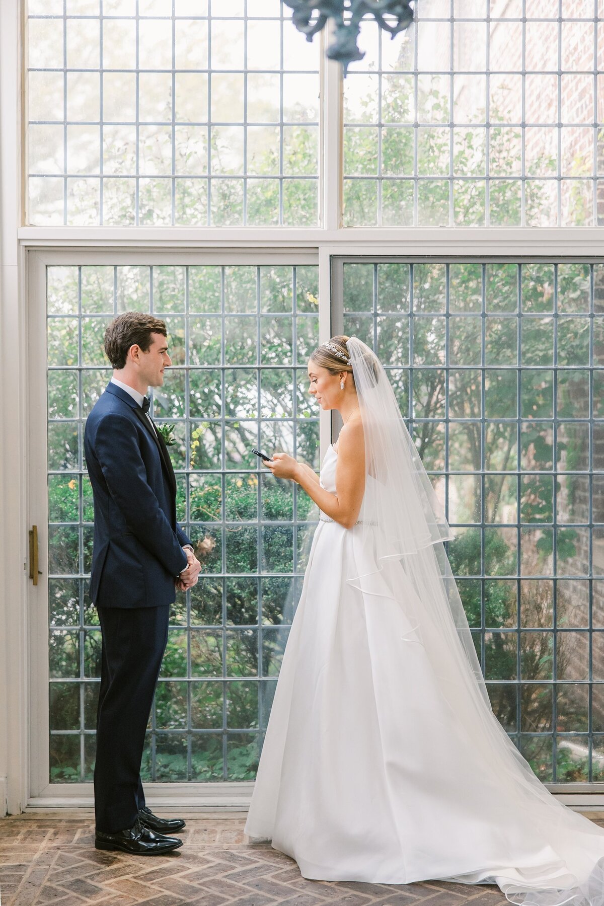 Bride and groom in conservatory reading vows while they face eachother