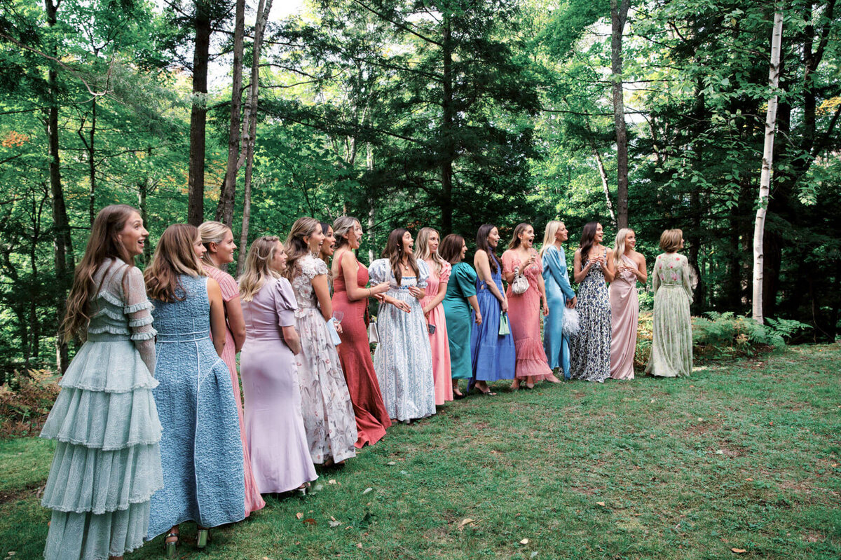 The bridesmaids are lined up outdoors with a lot of trees in the background at The Ausable Club, New York.