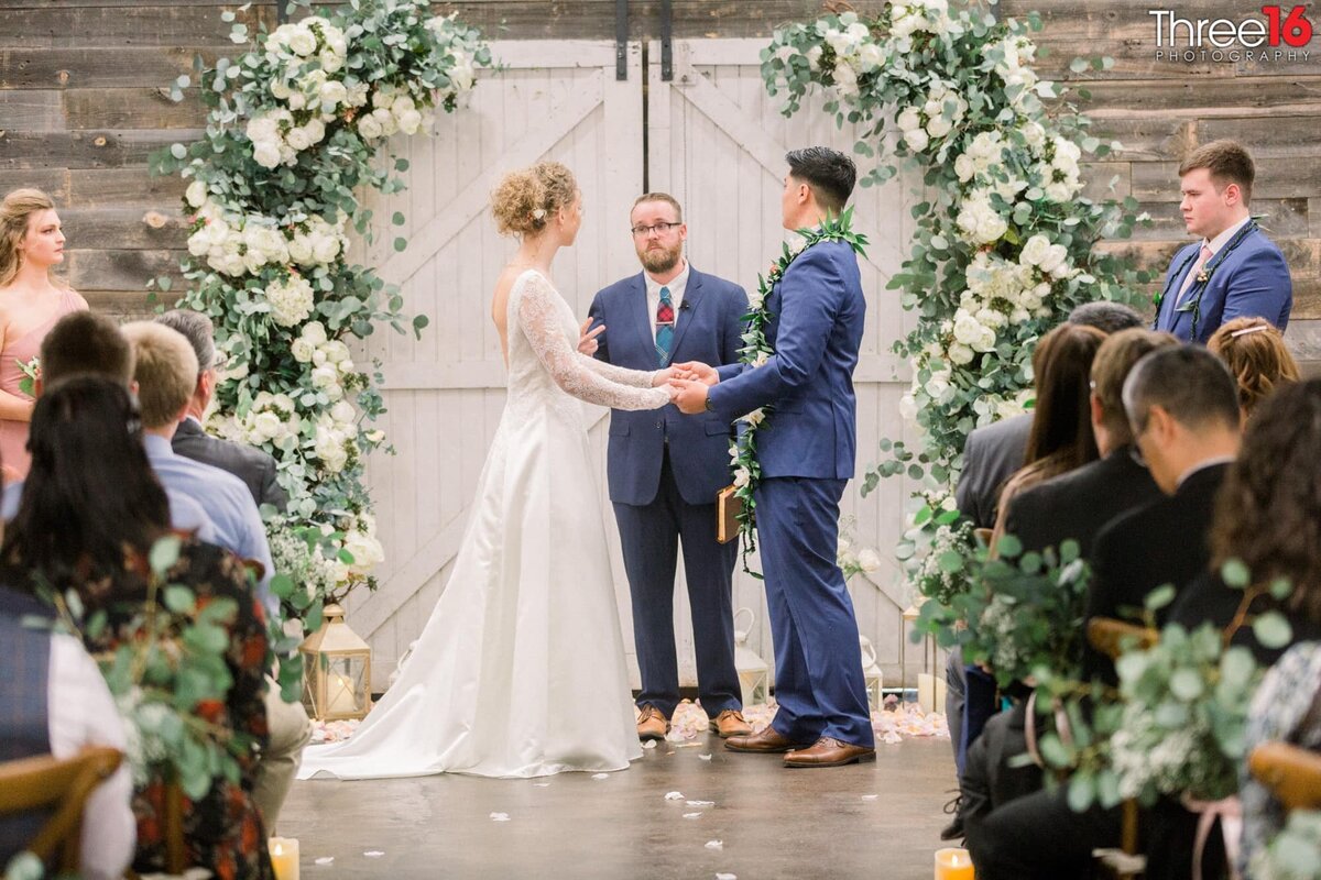 Bride and Groom hold hands as they look at the officiant during their vows
