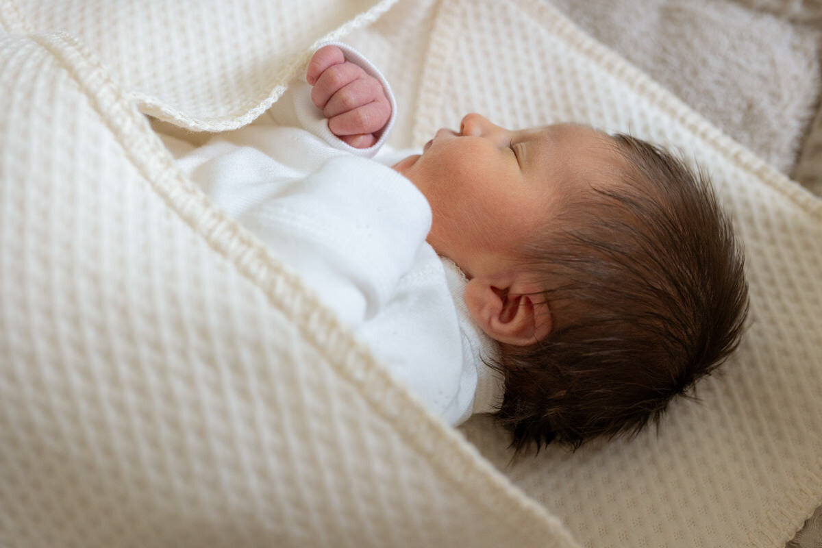 pasgeboren baby in wikkeldoek in box
