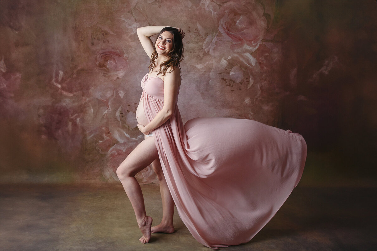 Pretty mom to be wearing a pink flowing maternity gown