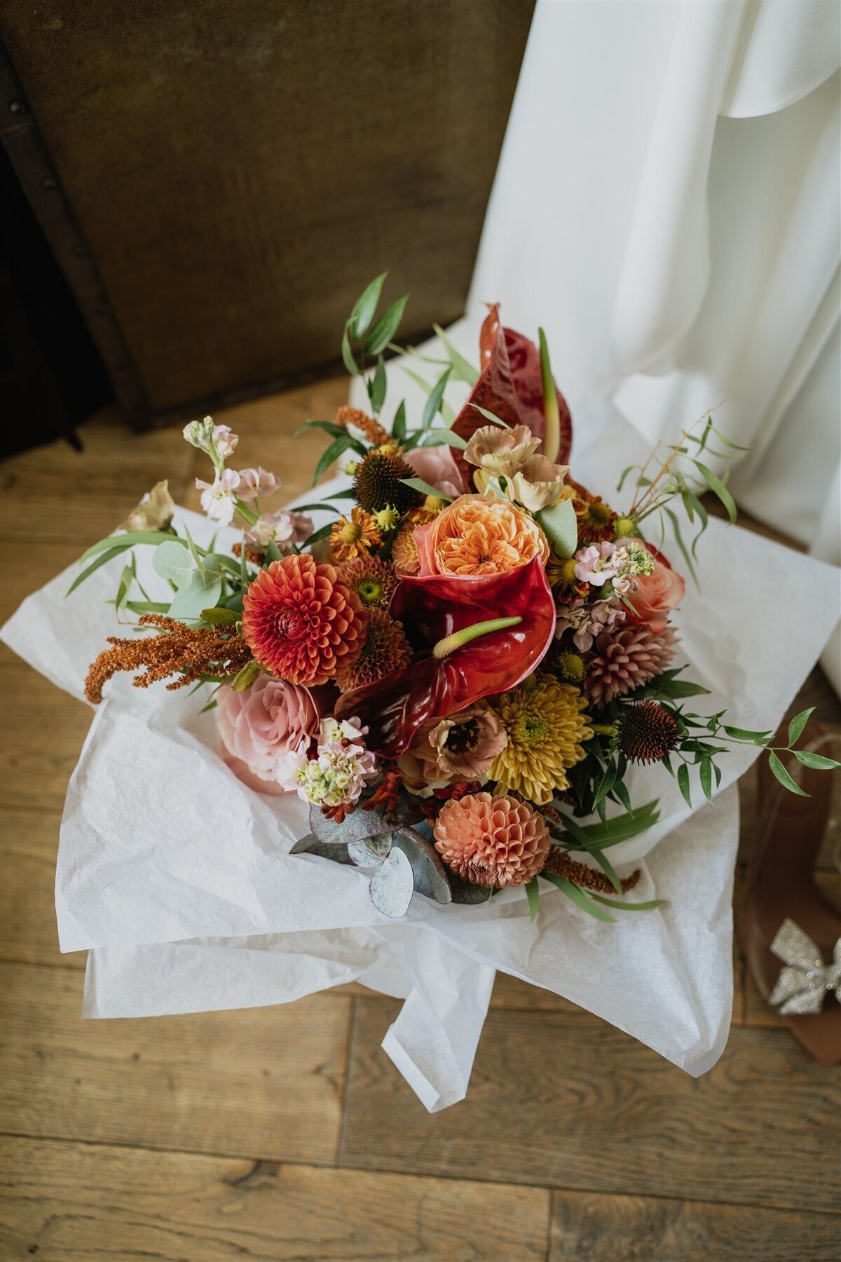 Autumnal flowers are photographed beside a wedding dress in the main bedroom at Logie Country House.
