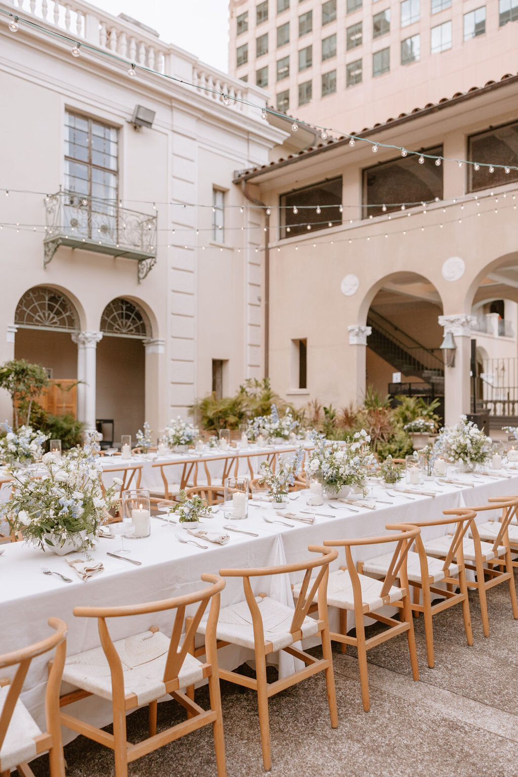 Wishbone chairs and long rectangle reception table with blue and white flowers on top