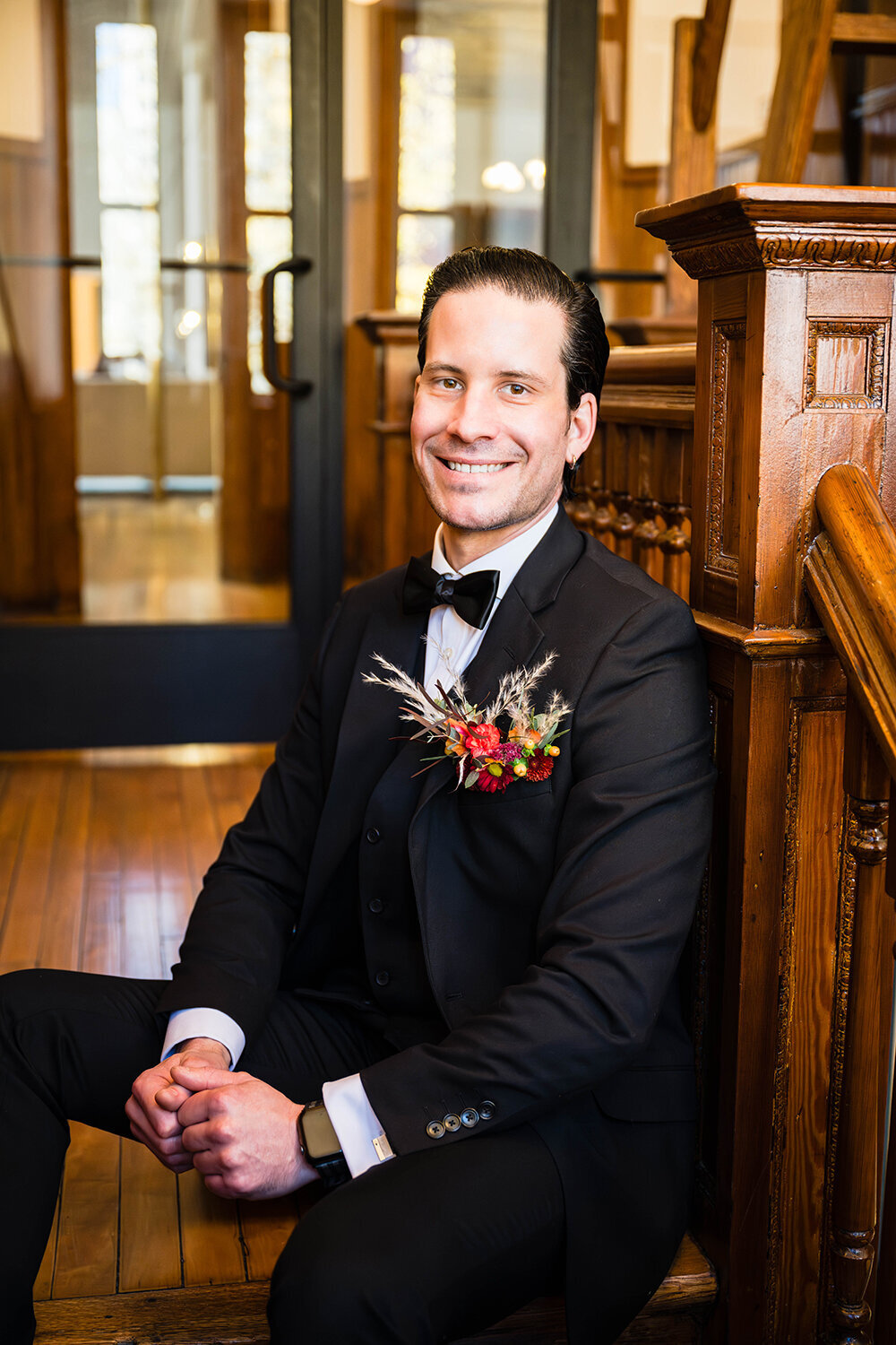 A groom sits at the top of a stairwell in a hotel in Downtown Roanoke for formal portraits on his elopement day.