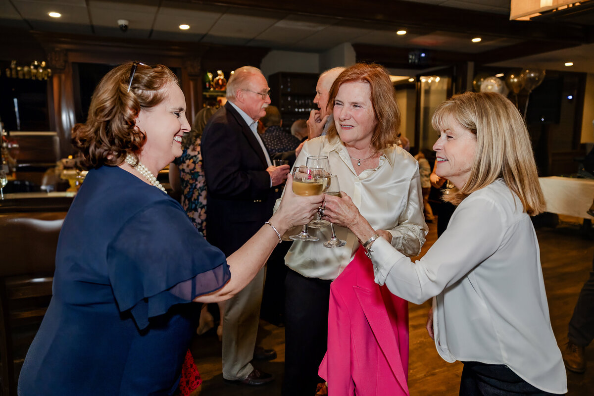 Women clinking wine glasses in a toast at an anniversary party