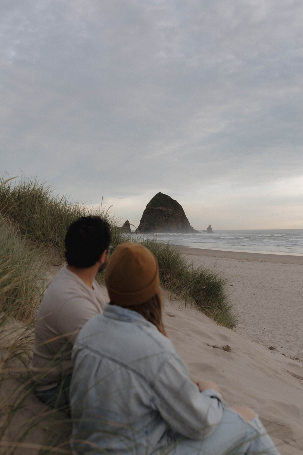 A breathtaking view of a couple looking out at Haystack Rock on the Oregon coast, a destination wedding and elopement setting.