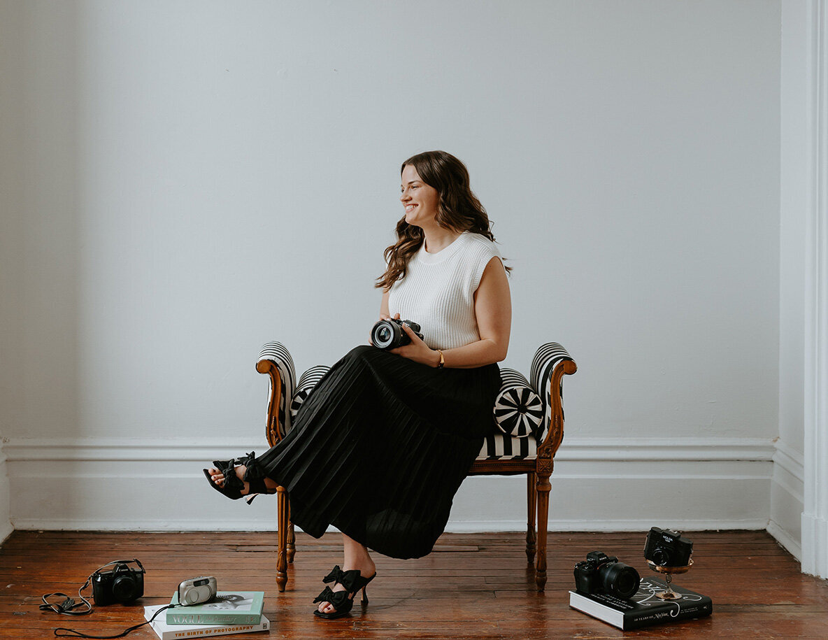 Stevie Davis sitting on a chair, holding her camera, ready to capture moments.
