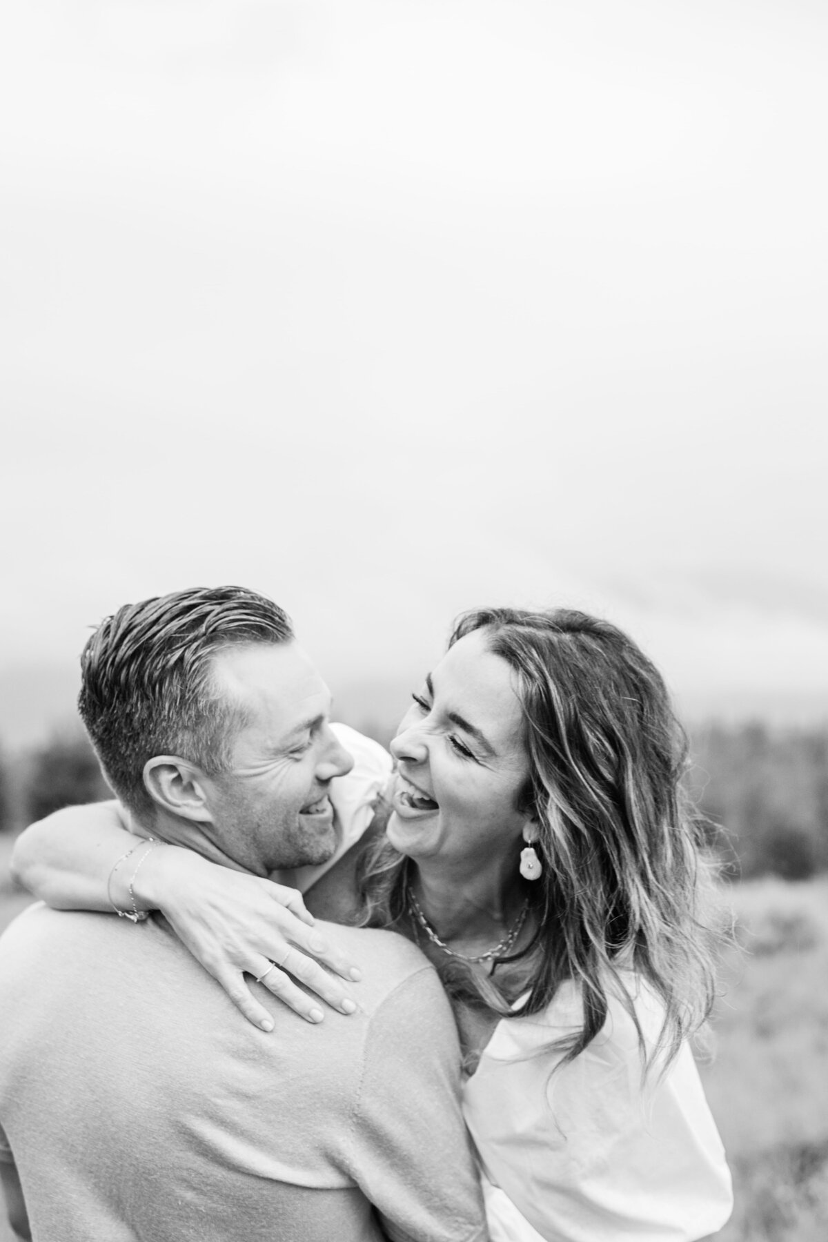 A black and white Breckenridge Couples Photographer image of a couple laughing and hugging in the mountains