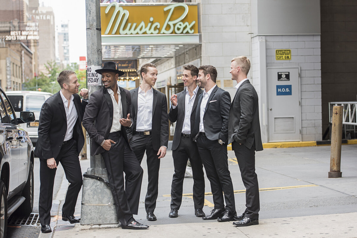 A group of people in suits standing on a city sidewalk