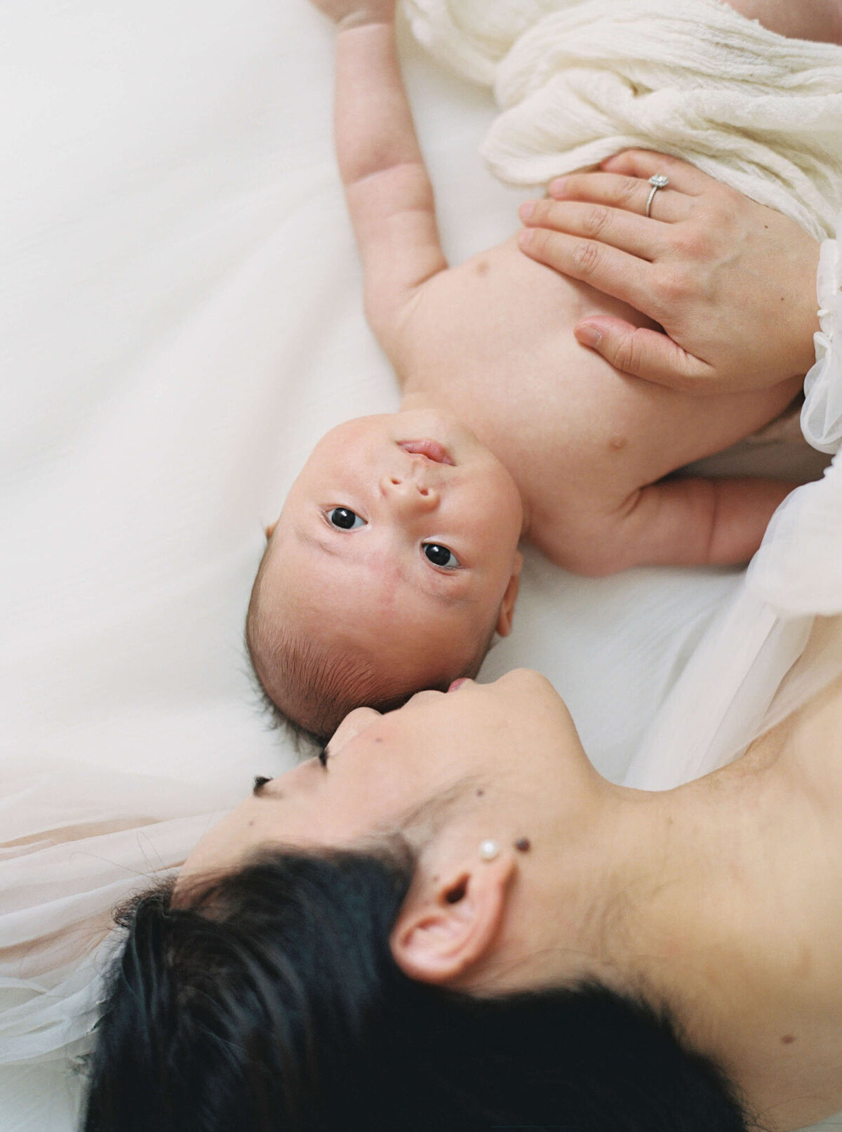 Mother laying on bed for newborn photos with Bay Area newborn photographer session.