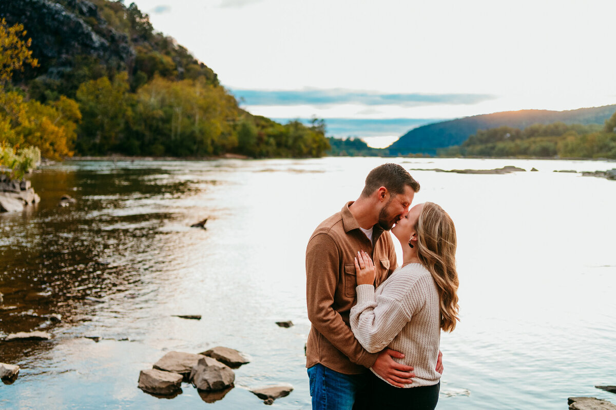 Couple embracing by the river with mountains in the background