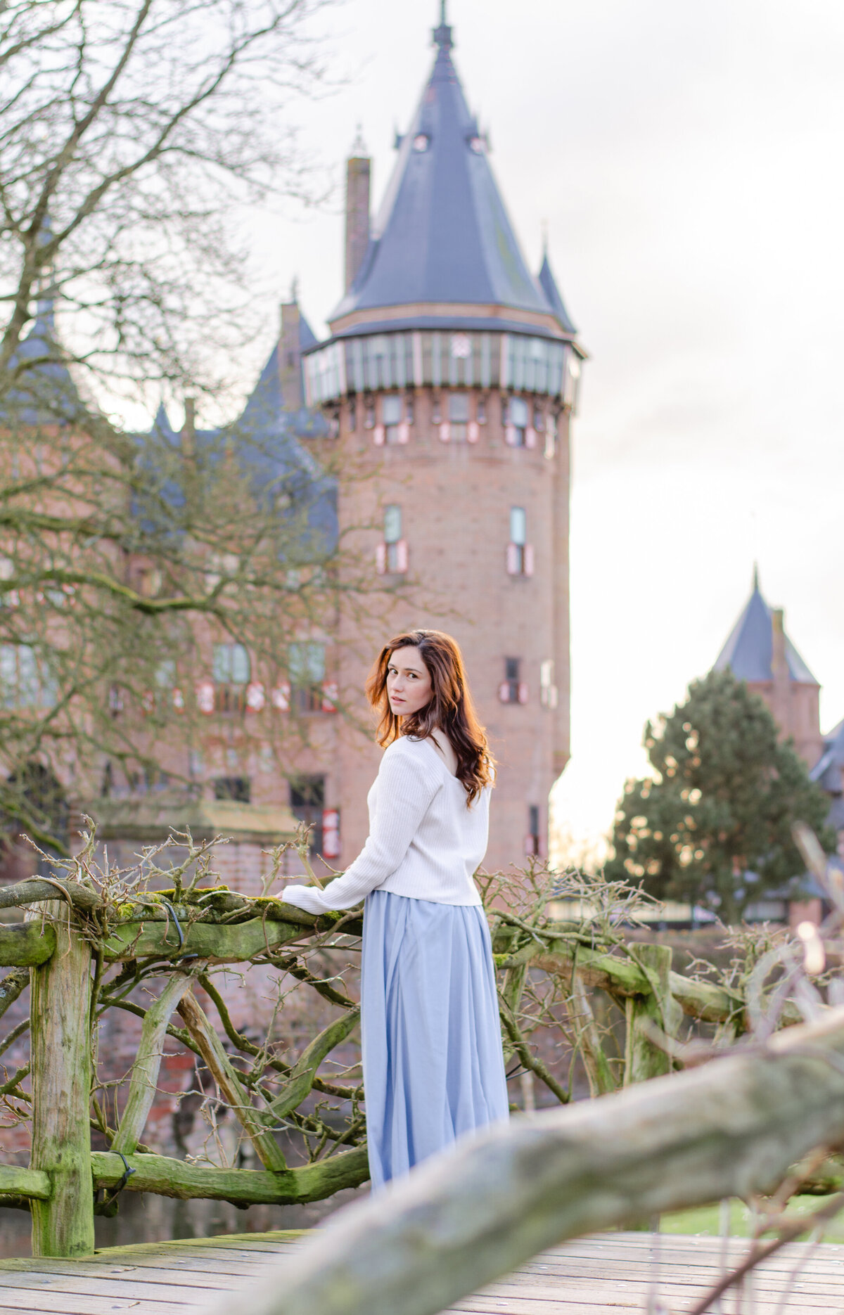 woman on bridge with netherlands fairytale castle de haar behind