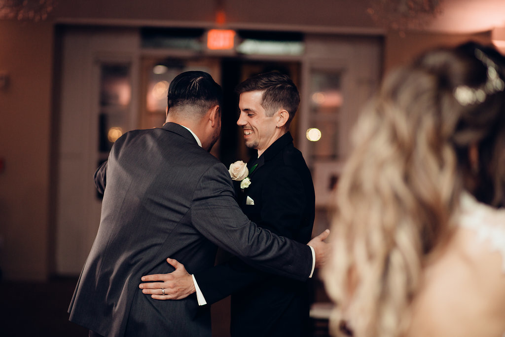 Wedding Photograph Of Groom Laughing While Dancing With a Man In Gray Suit Los Angeles