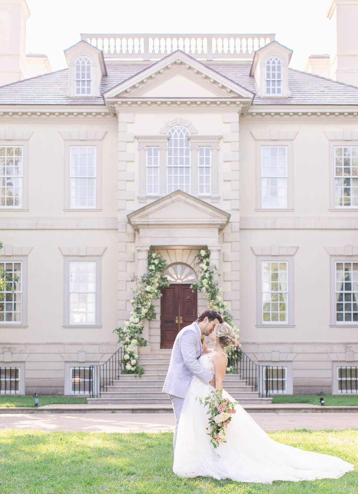 Bride and Groom kiss in front of Great Marsh Estate. Captured by Bethany Aubre Photography.