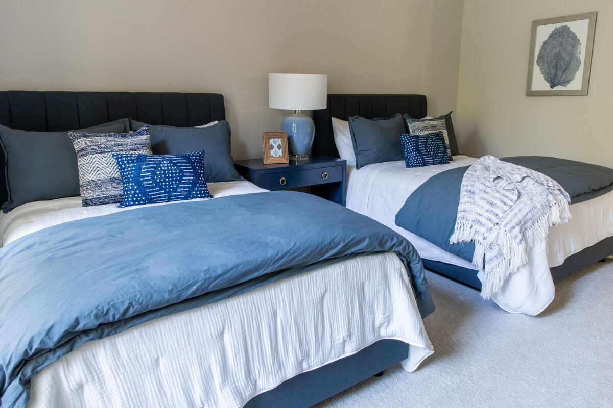 Cozy bedroom in Kiawah Island, SC, with a navy and white color palette, layered bedding, and stylish decor.