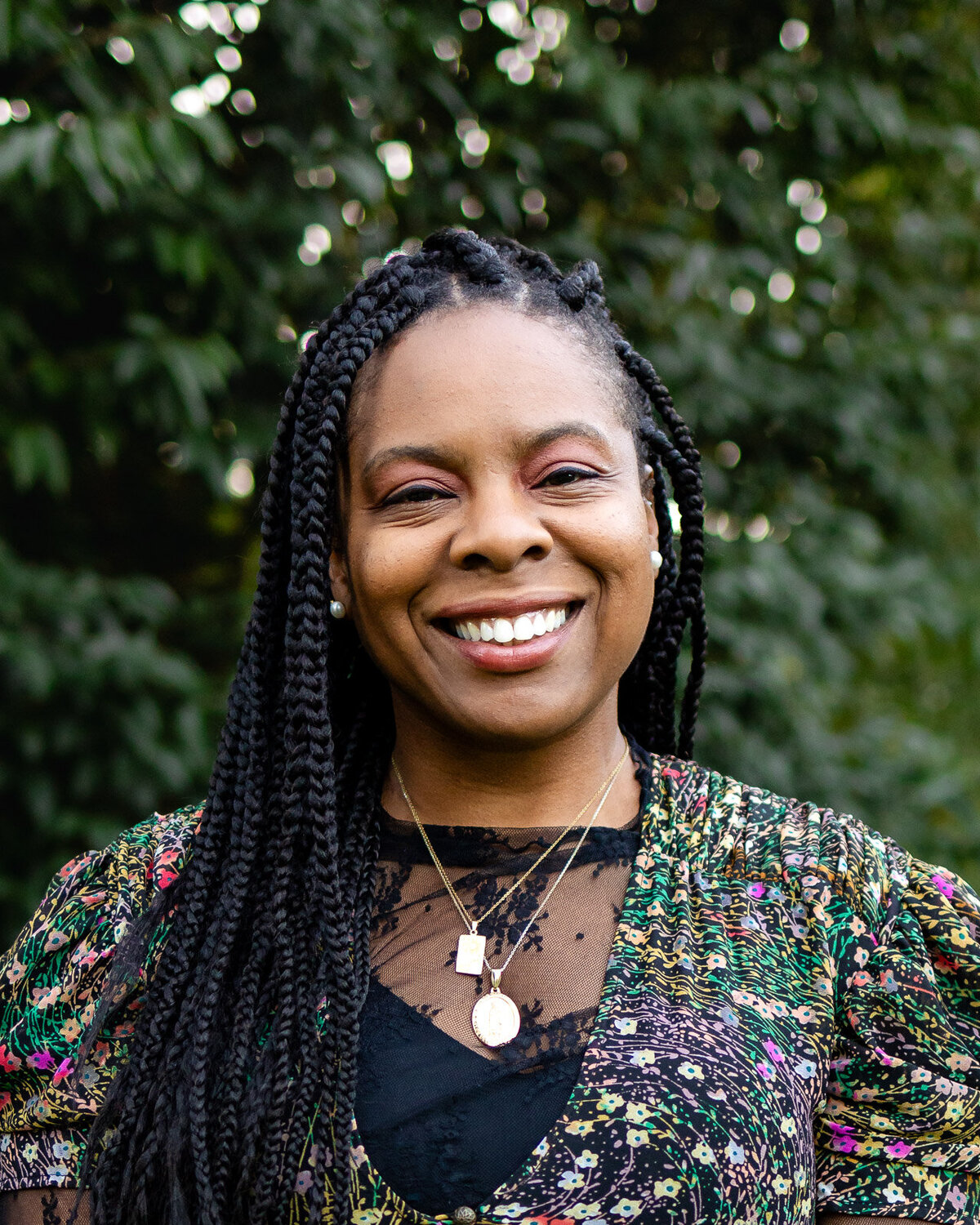 Outdoor professional headshot of a smiling woman featured in the Bay Area Headshot Portfolio with a leafy background – Ellobelle Photography