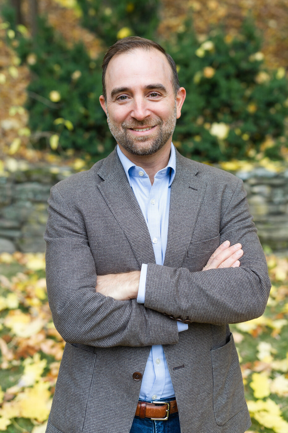 Professional headshot of Griff Resch posed with arms crossed and smiling on a fall day in Boston.