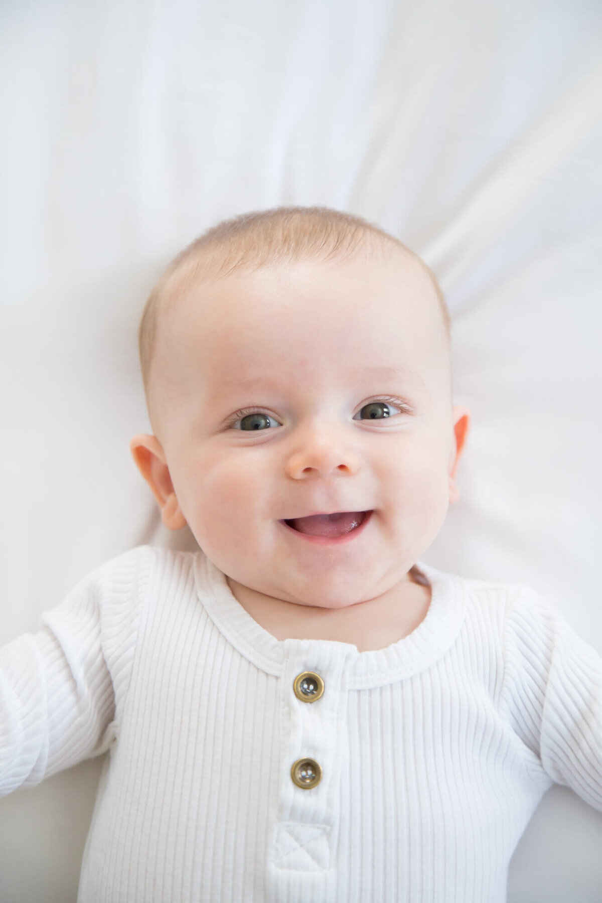 happy infant boy smiling joyfully on a white bed