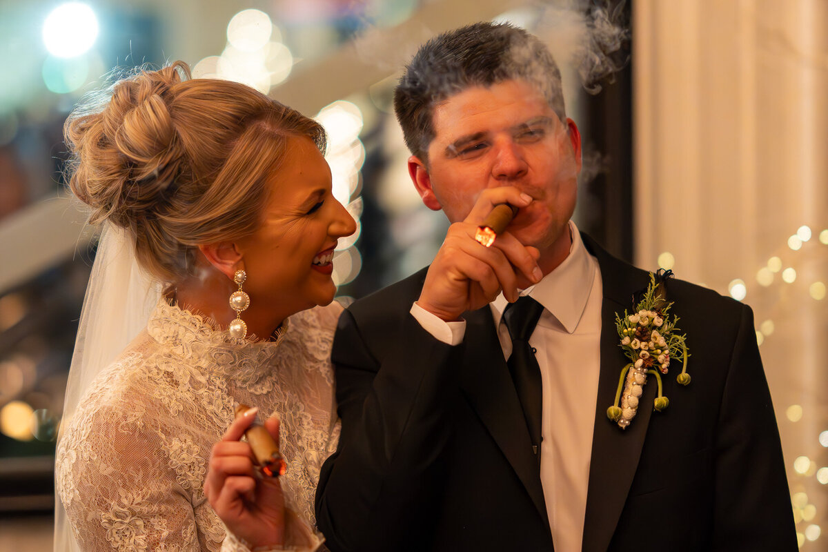 bride and groom celebrating while smoking and holding cigars.